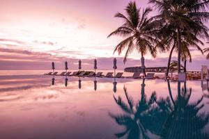 Luxury swimming pool on the beach, tranquil scene of exotic tropical landscape with copy space, summer background for vacation holidays. Beautiful poolside and sunset sky. Luxurious tropical beach photo