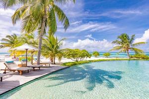 Beautiful luxury umbrella and chair around outdoor swimming pool in hotel and resort with coconut palm tree on blue sky. Luxurious summer vacation and holiday banner. Boost up color Processing photo