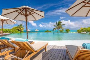 Beautiful luxury umbrella and chair around outdoor swimming pool in hotel and resort with coconut palm tree on blue sky. Luxurious summer vacation and holiday banner. Boost up color Processing photo