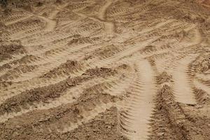 Tire track mark lines shape on dry sand background. Trail tyre imprint from heavy machinery. Vehicle shape. Road construction site backdrop concept. Trace of wheel pattern on mud. Nature texture. photo