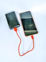 teléfono celular que se está cargando usando un banco de energía con fondo blanco aislado foto