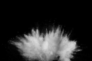 Bizarre forms of of white powder explosion cloud against dark background.Launched white dust splash on black background. photo