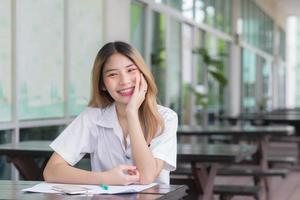 Young Asian girls students is using smart phone to search information for a study report she smiled happily while sitting in the university. photo