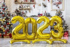 bolas doradas en forma de números 2023 en el fondo de un árbol de navidad. la gente está celebrando el año nuevo, esperando, anticipando. el concepto de año nuevo y celebración. foto