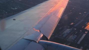 Orange reflection of the setting sun on the metal surface of an airplane wing. Airplane flies for landing with sunset lighting video