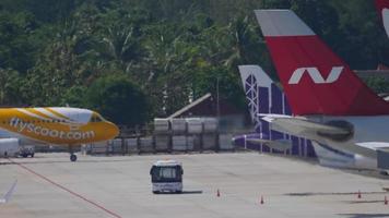 PHUKET, THAILAND NOVEMBER 27, 2019 - Airbus A320 of Scoot taxiing to the parking lot at Phuket airport, side view. Haze on the airfield. Tourism and travel concept video