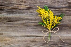 Yellow spring Mimosa bouquet with bow on a rustic wooden background with copyspace. photo