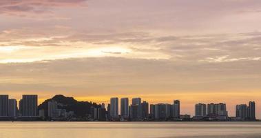 Timelapse silhuett se av vid vatten stad med höghus skyskrapa byggnad nära hav kust strand medan solnedgång solnedgång tid med vanilj skymning himmel video