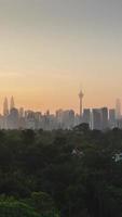 Vista vertical del paisaje de lapso de tiempo del área del distrito del centro de la ciudad de Kuala Lumpur con muchos rascacielos que construyen torres de estilo moderno de gran altura con un hermoso cielo de crepúsculo de la puesta del sol de vainilla video