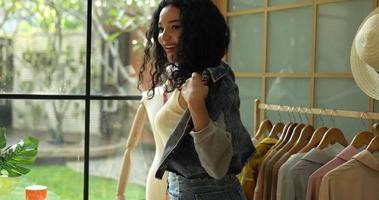 Primer plano de mano, joven diseñadora de moda que usa un abrigo de jeans sobre un vestido informal en un estudio de ropa de moda, una pequeña empresa y un concepto empresarial. video