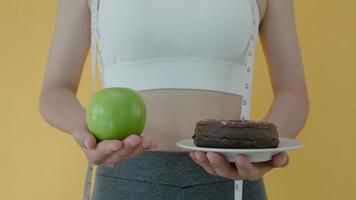 mulheres de corpo magro escolhem durante alimentos saudáveis e junk food, mulheres escolhem maçã verde para dieta. boa comida saudável. perda de peso, equilíbrio, controle, redução de gordura, baixas calorias, rotinas, exercícios. video