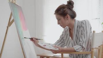 bellissimo femmina artista uso preparare dipingere per astratto arte e creare capolavoro. pittore dipingere con acquerelli o olio nel studio Casa. donna godere pittura come passatempo. opera ricreazione, relax, lavoro. video