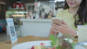 une femme utilise un smartphone pour scanner le code qr pour payer au café-restaurant avec un paiement numérique sans espèces. choisissez le menu et commandez accumulez la remise. portefeuille électronique, technologie, paiement en ligne, carte de crédit, application bancaire.