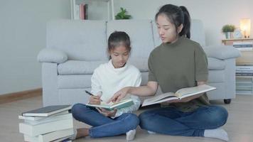 Mother teaching lesson for daughter. Asian young little girl learn at home. Do homework with kind mother help, encourage for exam. Asia girl happy Homeschool. Mom advise education together.