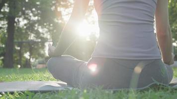mujer practicando meditar en el parque. mujer asiática haciendo ejercicios por la mañana. equilibrio, recreación, relajación, calma, buena salud, feliz, relax, estilo de vida saludable, reducir el estrés, paz, actitud.