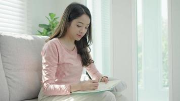 inspiration, écrivain, écriture, création, loisirs pour imaginer, belle jeune femme asiatique séduisante écrivant des idées sur un cahier, liste de choses à faire, bon travail de réflexion, journaliste, élégant, image de rêve, détente video