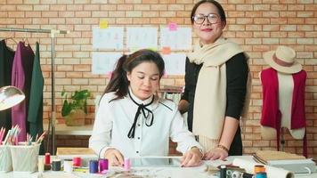Fashion team, Asian female designer and teen assistant in studio, arms crossed and smile, happy working with colorful thread and sewing for dress design, professional boutique tailor SME entrepreneur.