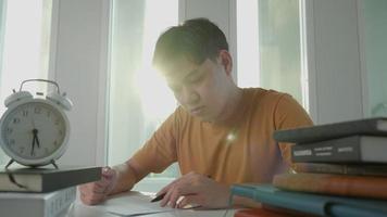 un étudiant asiatique a de l'anxiété à cause des examens, les hommes se préparent aux tests et apprennent les leçons à la bibliothèque. stress, désespoir, hâte, incompréhension lecture, découragement, attente, connaissance, fatigue video