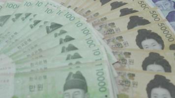 Moneda coreana, muchos billetes de banco coreanos colocados sobre la mesa. El won es la moneda de Corea que se usa para cambiar, comprar, vender, acumular e invertir en la gente de Corea. video