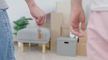 déménagement, déménagement. un couple tient le trousseau de clés de la maison dans un nouvel appartement, à l'intérieur de la pièce se trouvait une boîte en carton contenant des effets personnels et des meubles. emménager dans le nouvel appartement ou condominium video