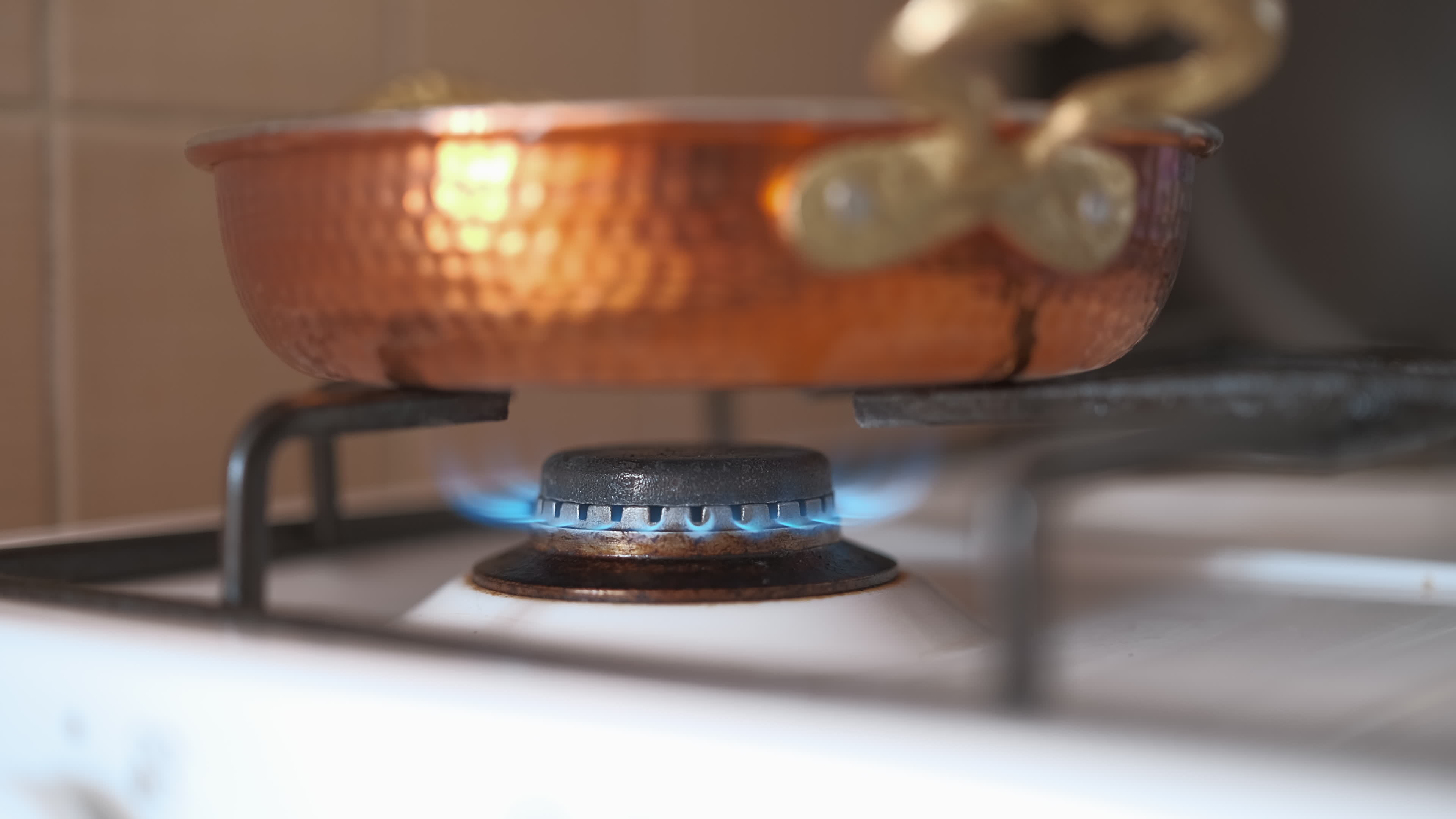 Copper frying pan on a gas stove closeup. Cooking in a saucepan on a