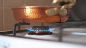 Copper frying pan on a gas stove close-up. Cooking in a saucepan on a gas stove open fire. Video 4k in real time.