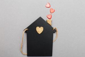 pequeña casa de juguete con corazones rojos de tubería sobre fondo gris. concepto de amor, familia foto