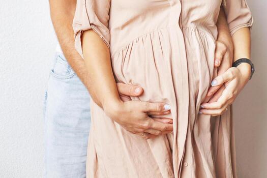 Young pregnant woman and husband hugging her belly close photo