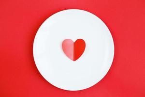 corazón en un plato blanco con el fondo rojo foto