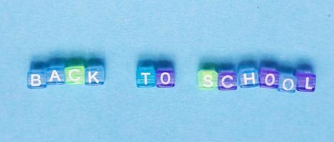 The inscription back to school made by multicolor plastic cubes on a blue background. photo