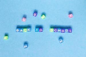 The inscription back to school made by multicolor plastic cubes on a blue background. photo