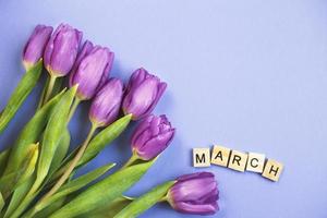 Purple bouquet of flowers tulips background with with the word march on veri peri background. photo