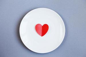 corazón rojo en un plato blanco sobre fondo gris foto
