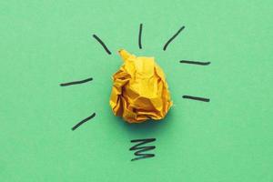 bombilla de papel amarillo arrugado como concepto de idea creativa e innovación en un fondo verde foto