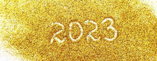 number 2023 written on golden confetti. christmas or new year background photo