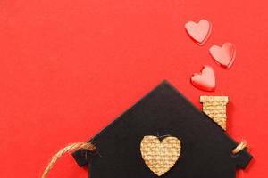 small toy house with red hearts from pipe on red background. Concept of love , family photo