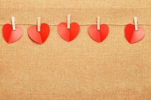 red hearts on clothes pin on brown textile background photo