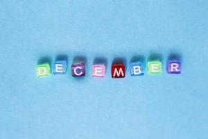 inscription december made by multicolor plastic cubes on a blue background. photo