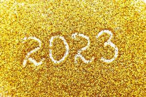 number 2023 written on golden confetti. christmas or new year background photo