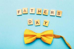 letras del día del padre feliz hechas con cubos de madera sobre un fondo azul con una corbata de moño amarilla foto