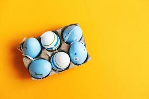 top view easter colorful handmade painted blue eggs in a box on orange background photo