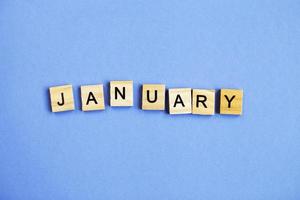 inscription January made by wooden cubes on a veri peri purple background. photo