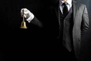 retrato de mayordomo en traje oscuro y guantes blancos con campana de latón. concepto de industria de servicios y hospitalidad profesional.
