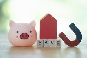 Red wood house placed on text of save and cute pig. Save to buy a home concept for property. photo