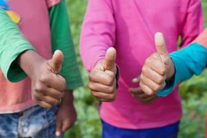 grupo de niños felices con las manos mostrando los pulgares hacia arriba en la escuela. aprendizaje, actividad, educación, escuela, trabajo en equipo y concepto cooperativo foto