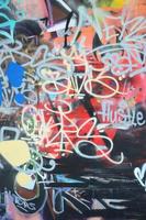 Close-up fragment of a graffiti drawing applied to the wall by aerosol paint. The wall is spoiled by a multitude of colorful signatures and tags from street artists and hooligans photo