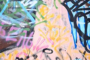 Close-up fragment of a graffiti drawing applied to the wall by aerosol paint. The wall is spoiled by a multitude of colorful signatures and tags from street artists and hooligans photo