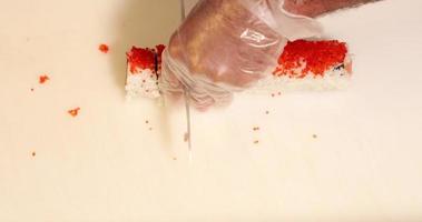 Chef Cutting The Sushi Rolls Using A KNife On A White Chopping Board.  - high angle shot video