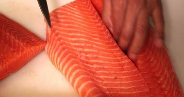 Küchenchef, der das frische Fleischfilet in zwei Hälften schneidet und für Sushi von einer Haut trennt. - Hochwinkelaufnahme video