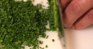 un' qualificato capocuoco affettare sottilmente il fresco verde cipolla erba cipollina su un' chopping tavola nel il cucina. - vicino su tiro video